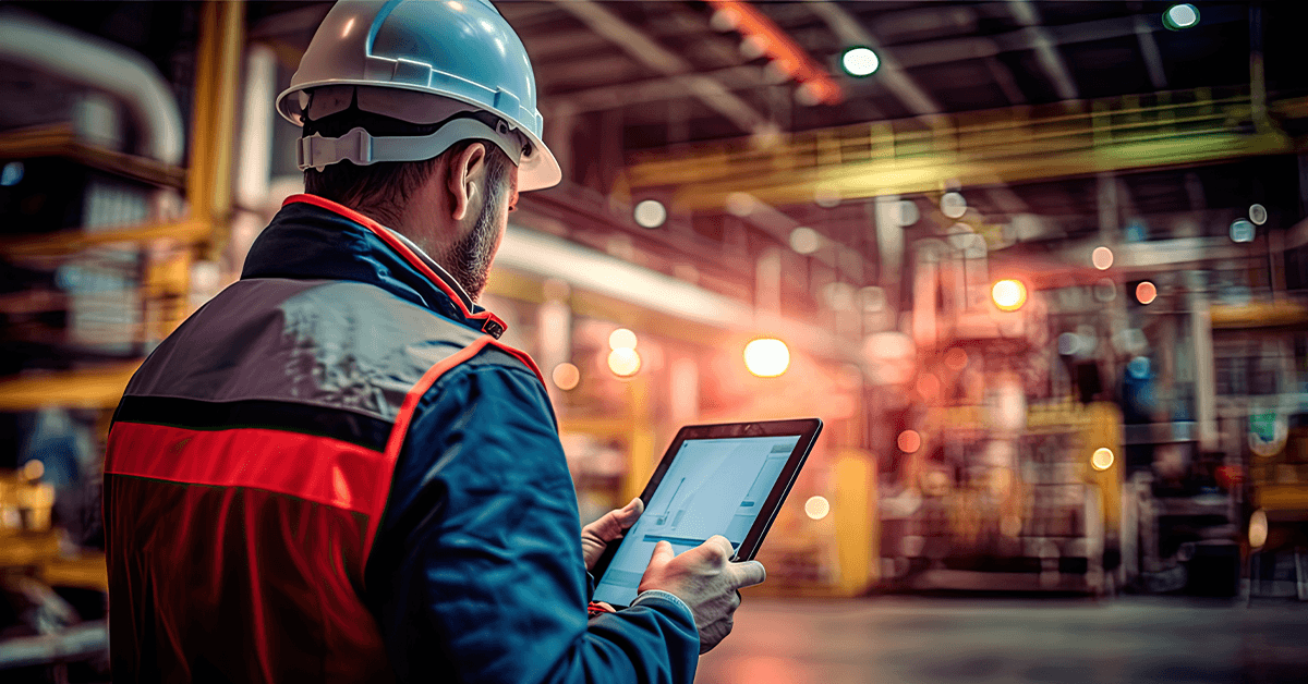 A manufacturing employee using technology while working inside a manufacturing facility