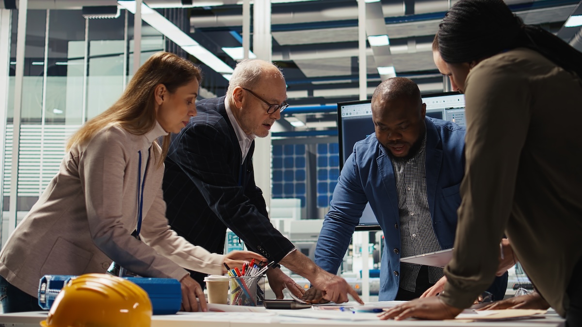 Industrial team reviewing marketing strategy and project plans on a factory floor